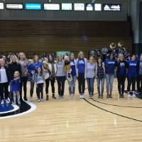 GVSU volleyball alumni and their kids pose for a photo on the volleyball court